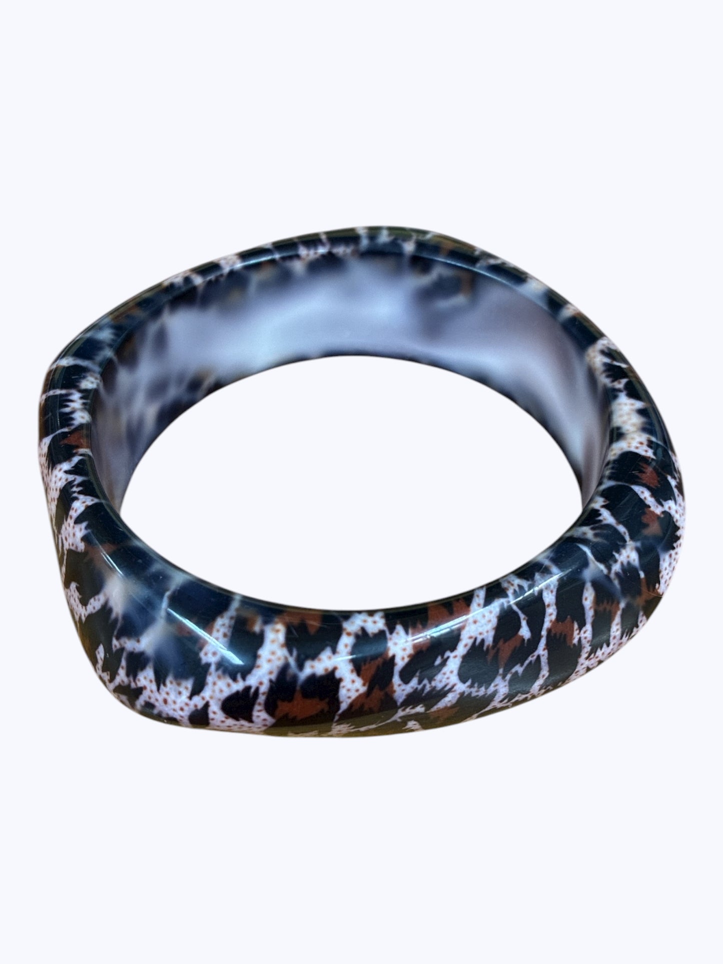 Modern acrylic bangle bracelet with a bold organic abstract pattern and smooth rounded silhouette.