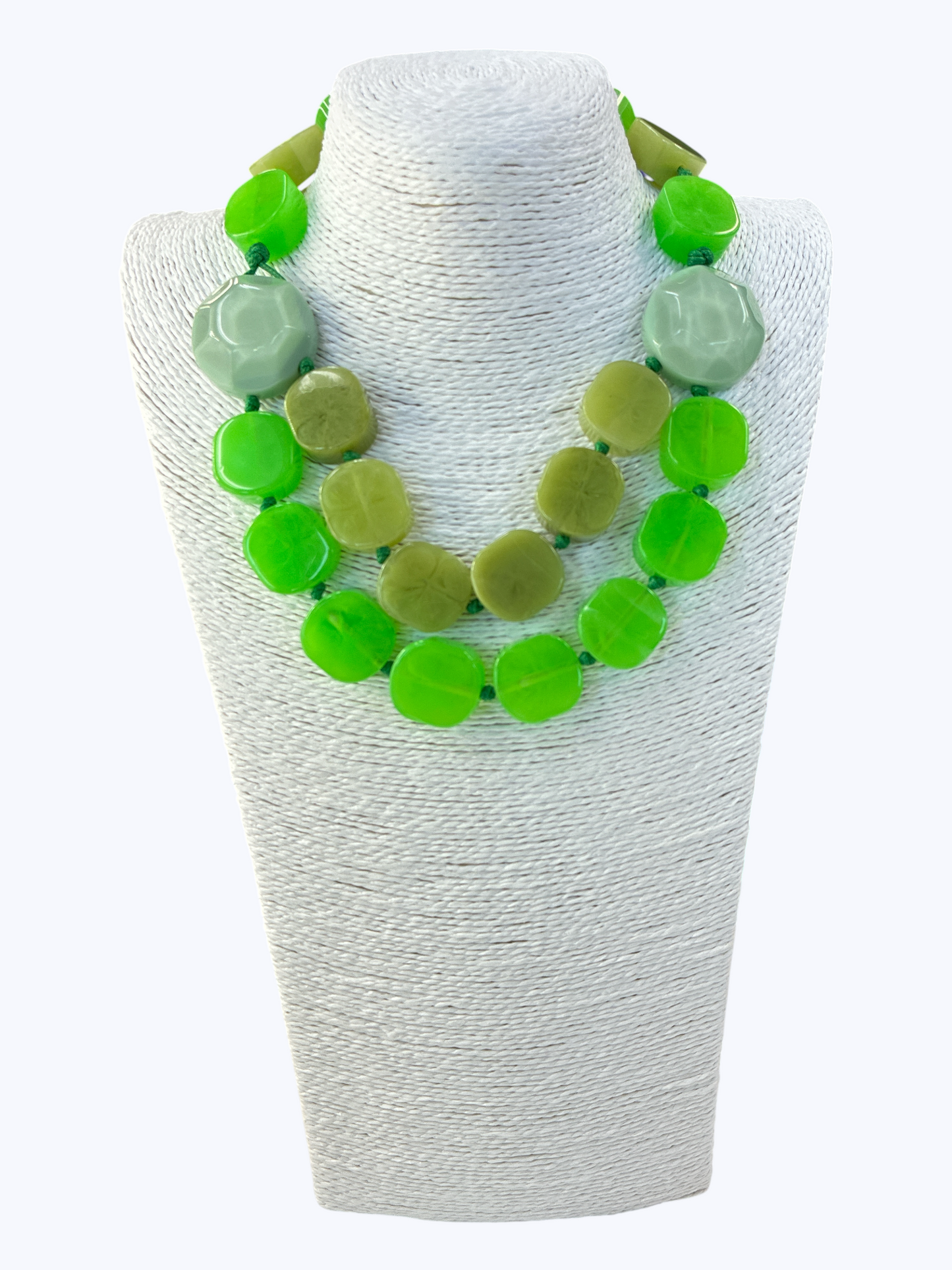 Necklace with green and light green beads on a white mannequin bust.