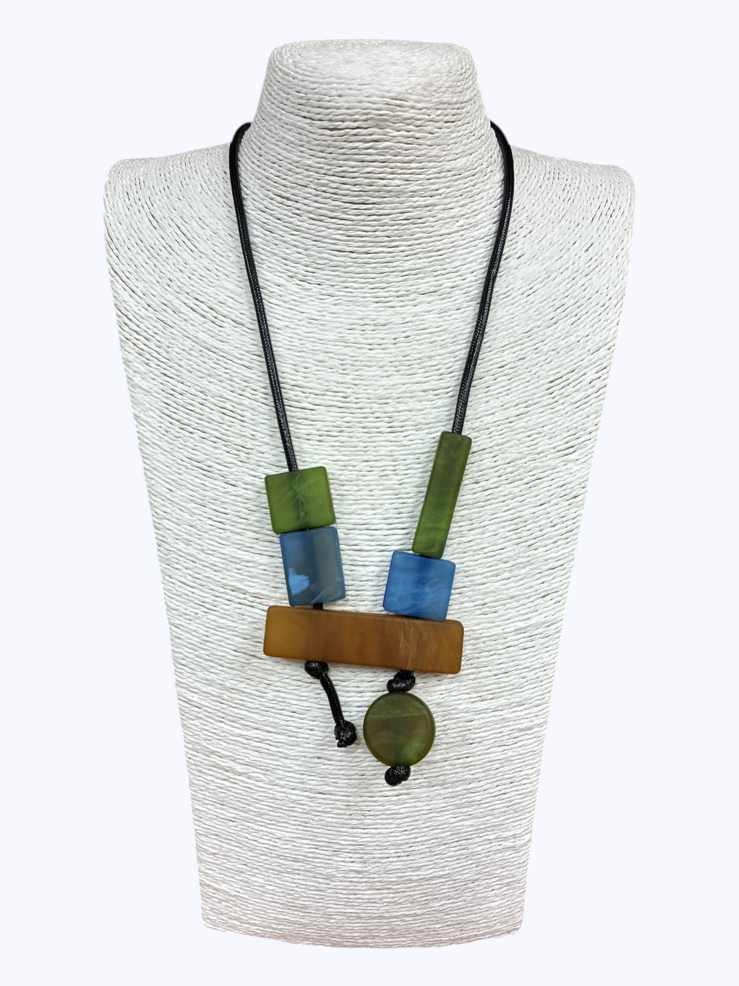 Long pendant necklace with geometric resin and wood-like blocks in a modern abstract arrangement on a cord, displayed on a mannequin bust