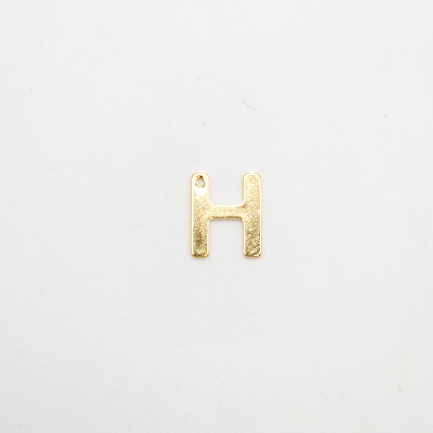 Gold letter 'H' charm on a white background