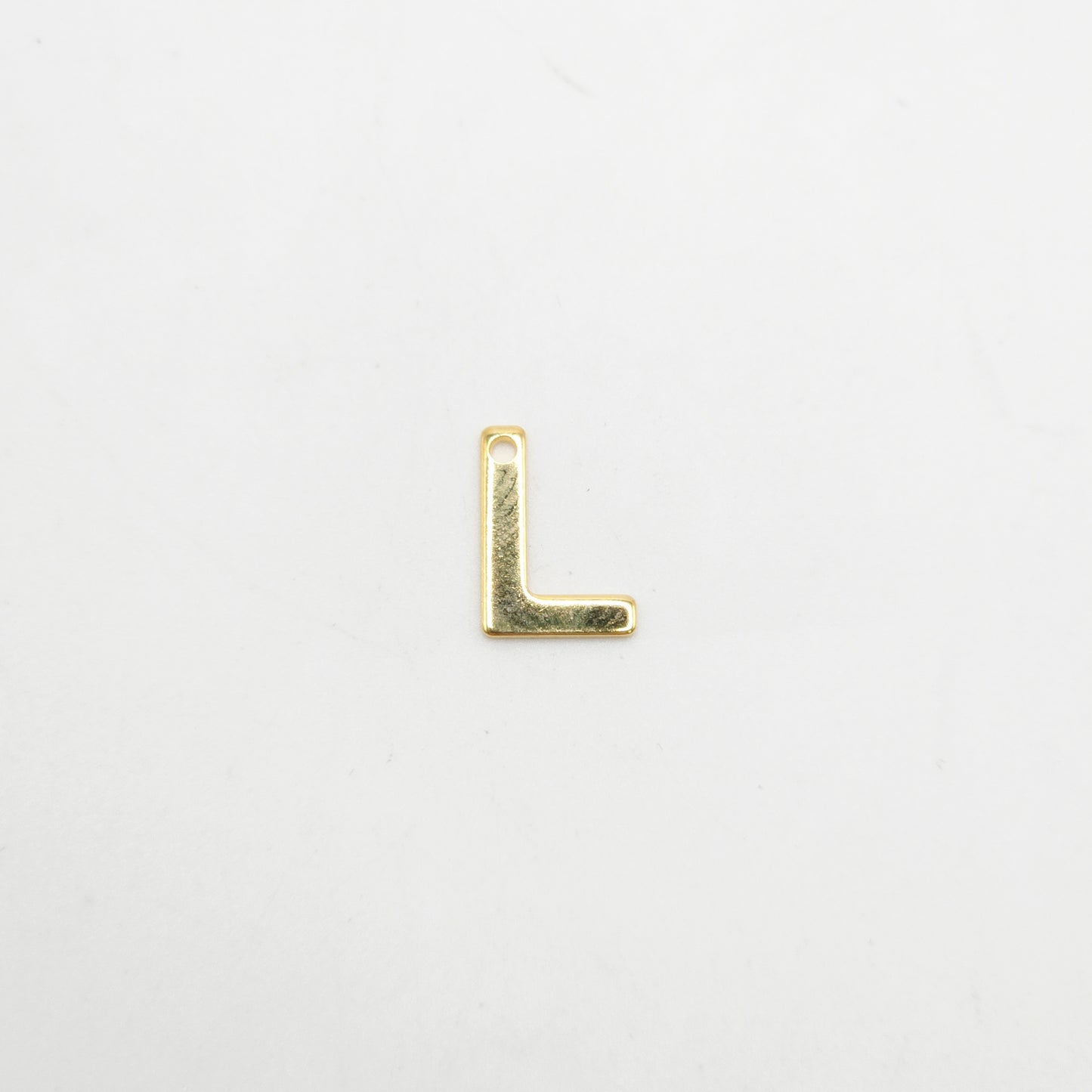 Gold letter 'L' charm on a light gray background