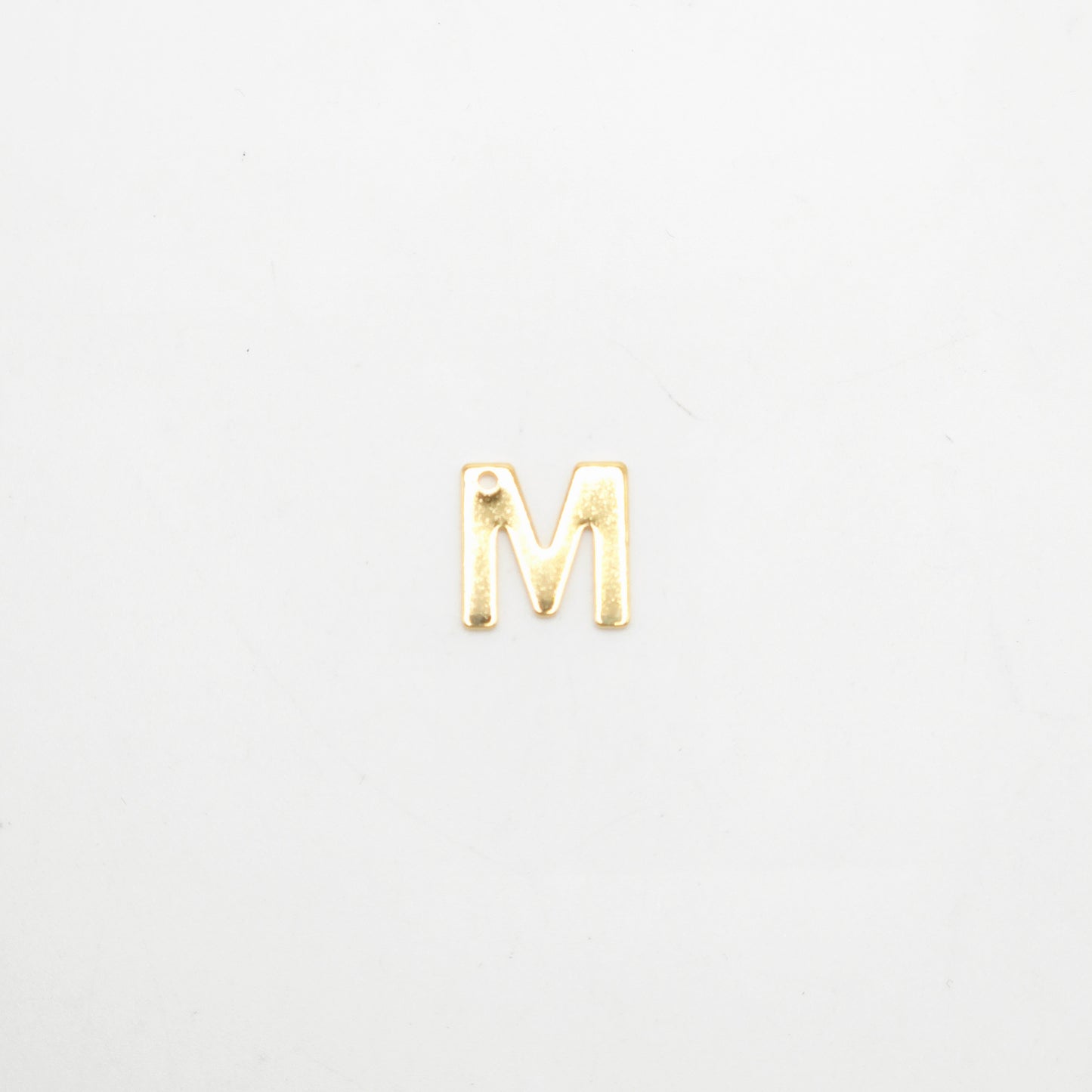 Gold letter 'M' charm on a white background