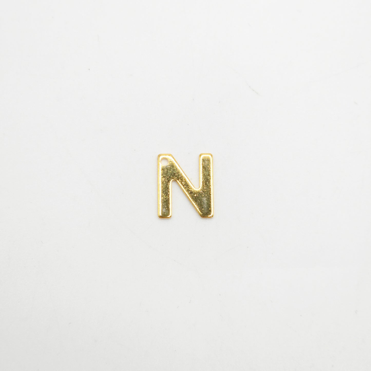 Gold letter 'N' charm on a light gray background