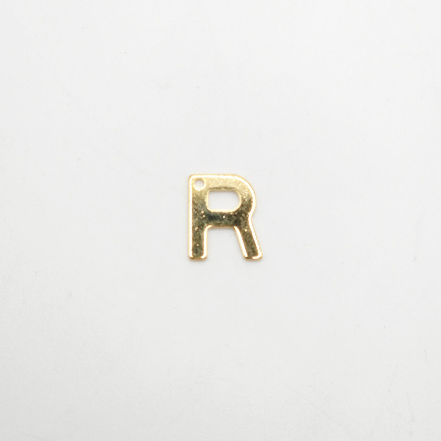Gold letter 'R' charm on a white background