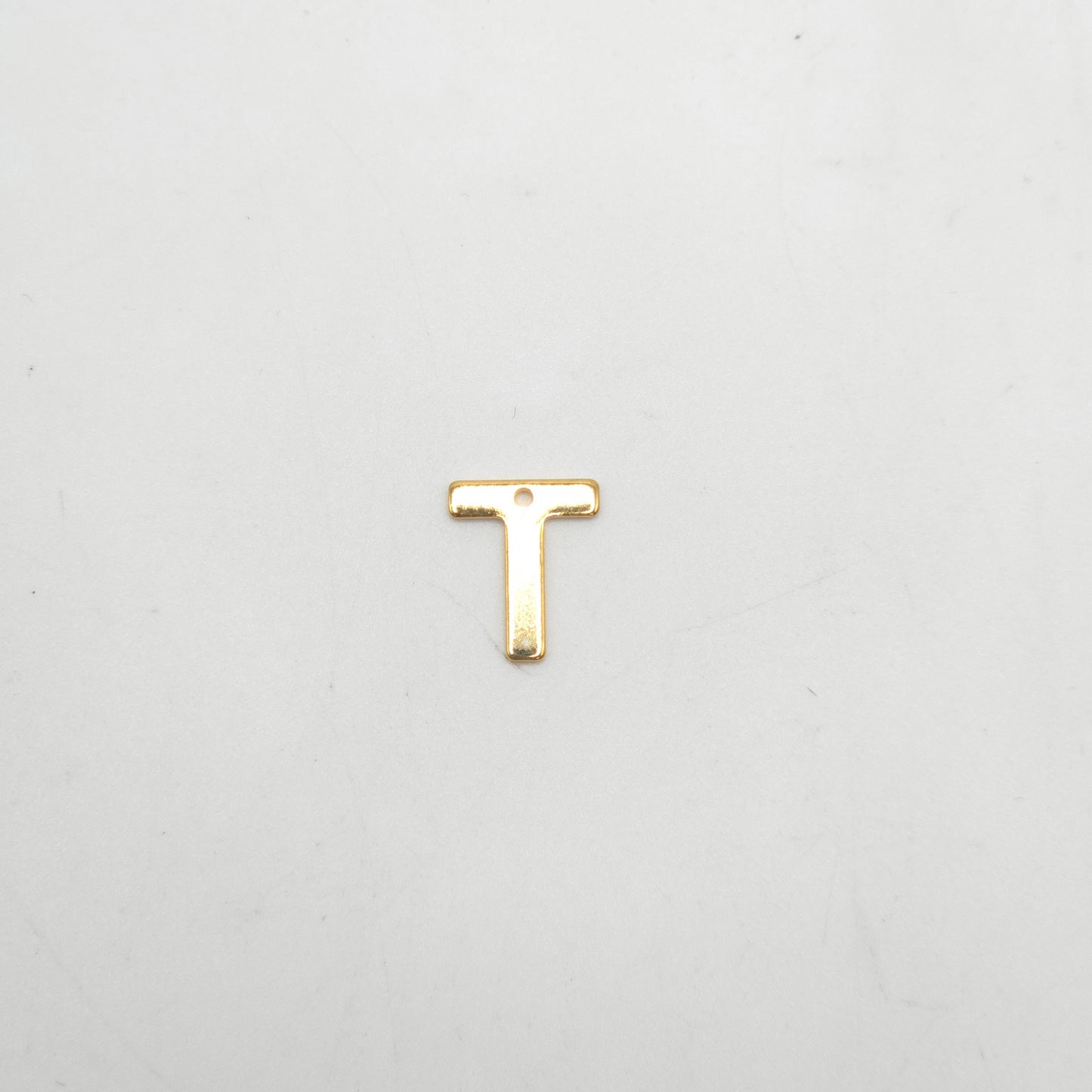 Gold letter 'T' charm on a light gray background