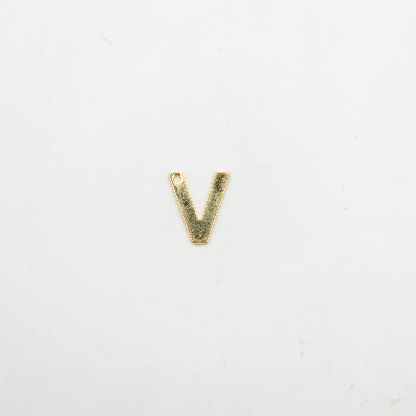 Gold letter 'V' charm on a white background