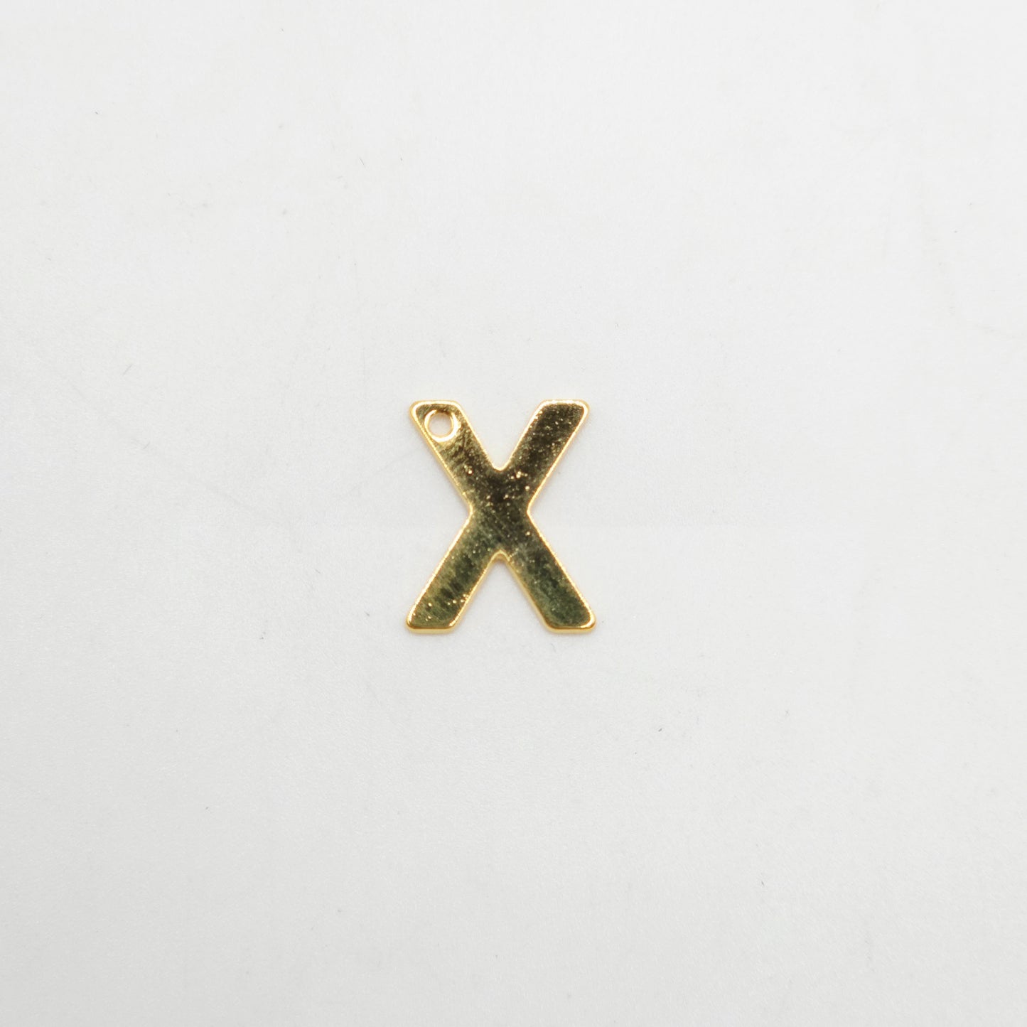 Gold letter 'X' charm on a white background
