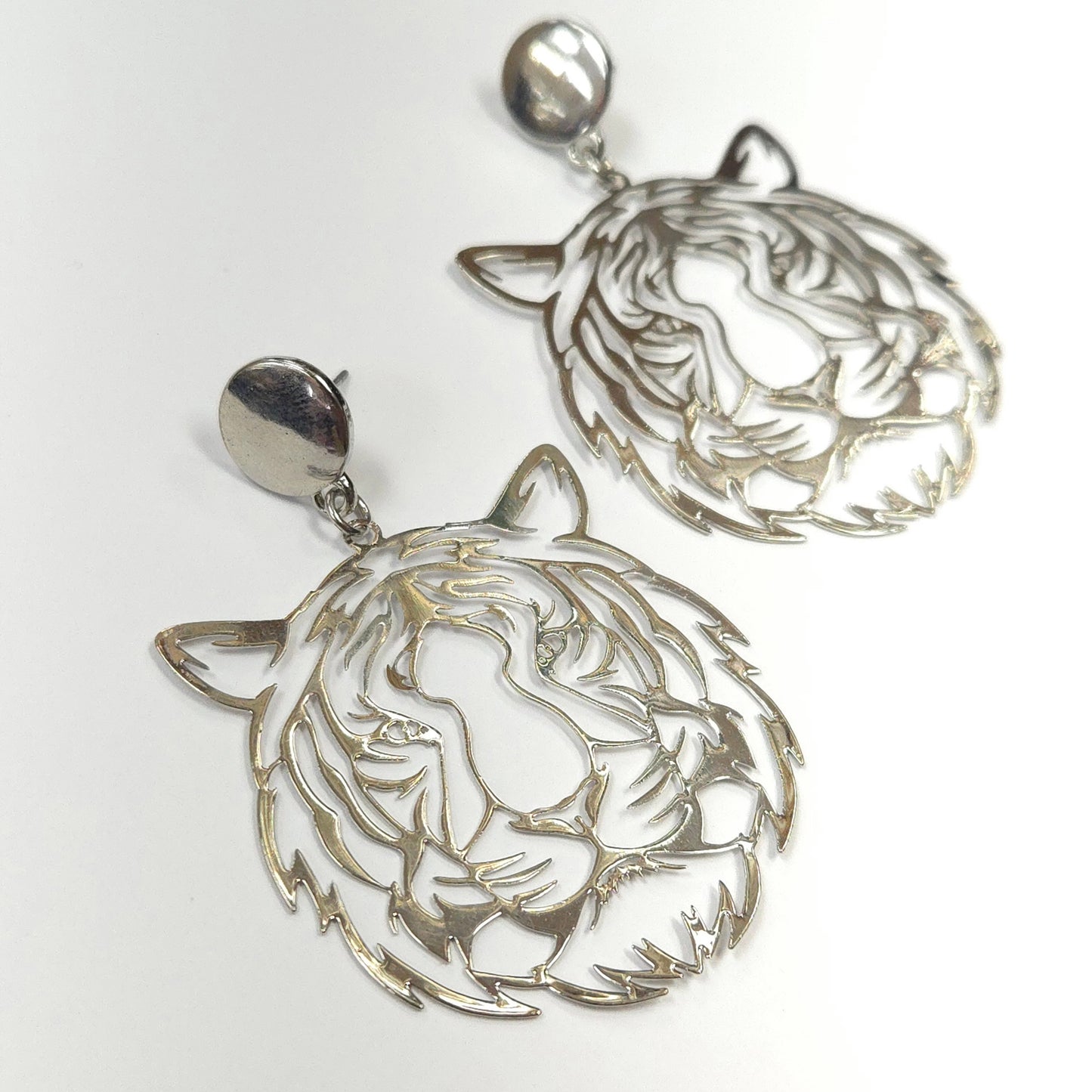 Silver earrings with intricate designs on a white background