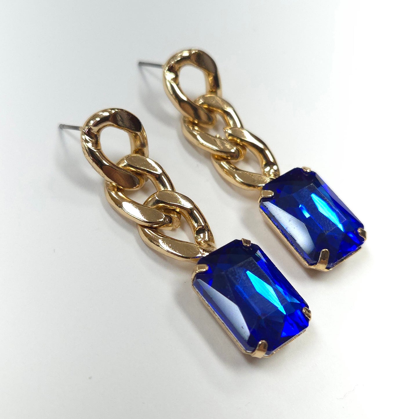 Gold chain earrings with blue gemstones on a white background