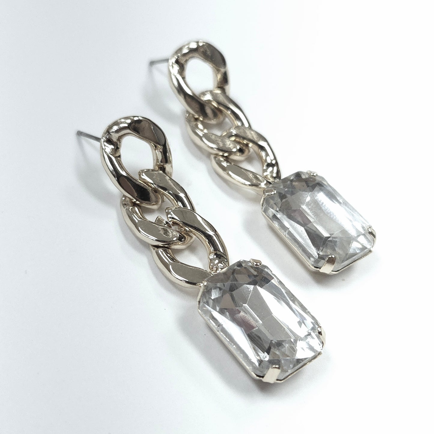 Silver chain earrings with clear gemstones on a white background