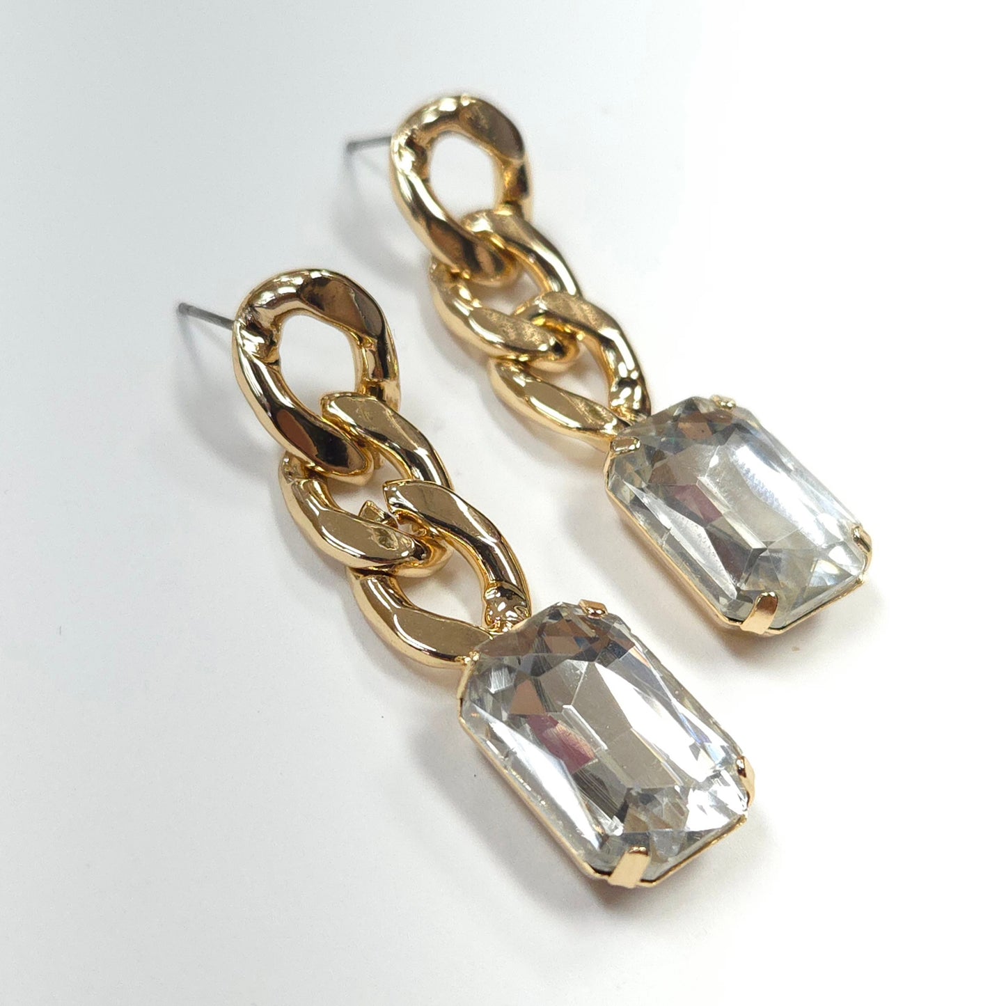 Gold chain earrings with clear gemstones on a white background
