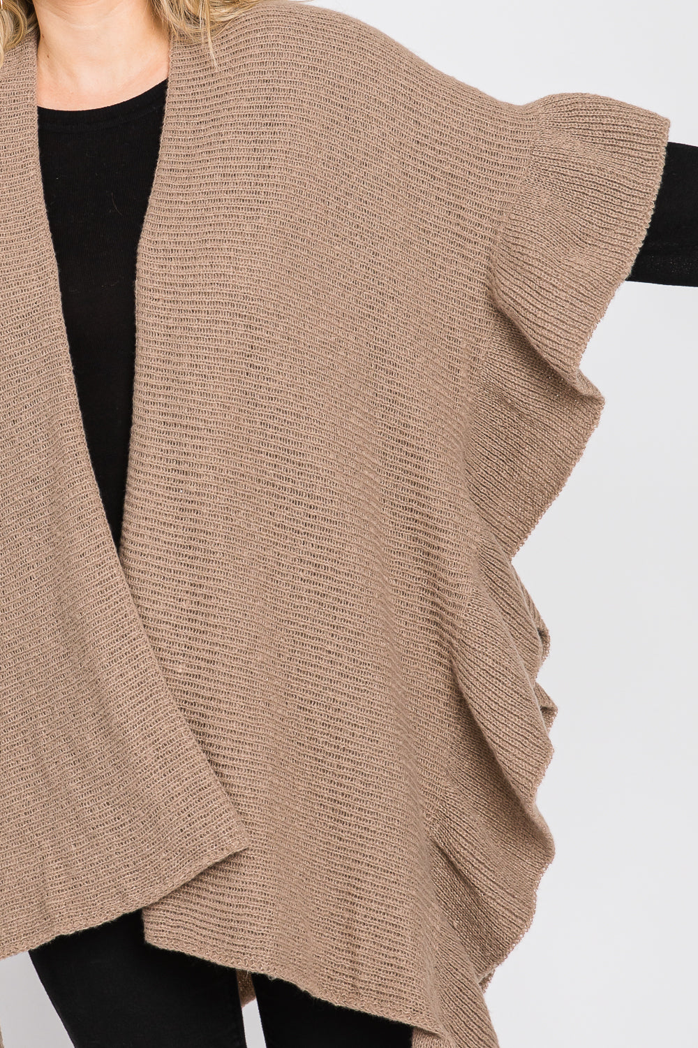 Beige knitted vest worn over a black top on a white background