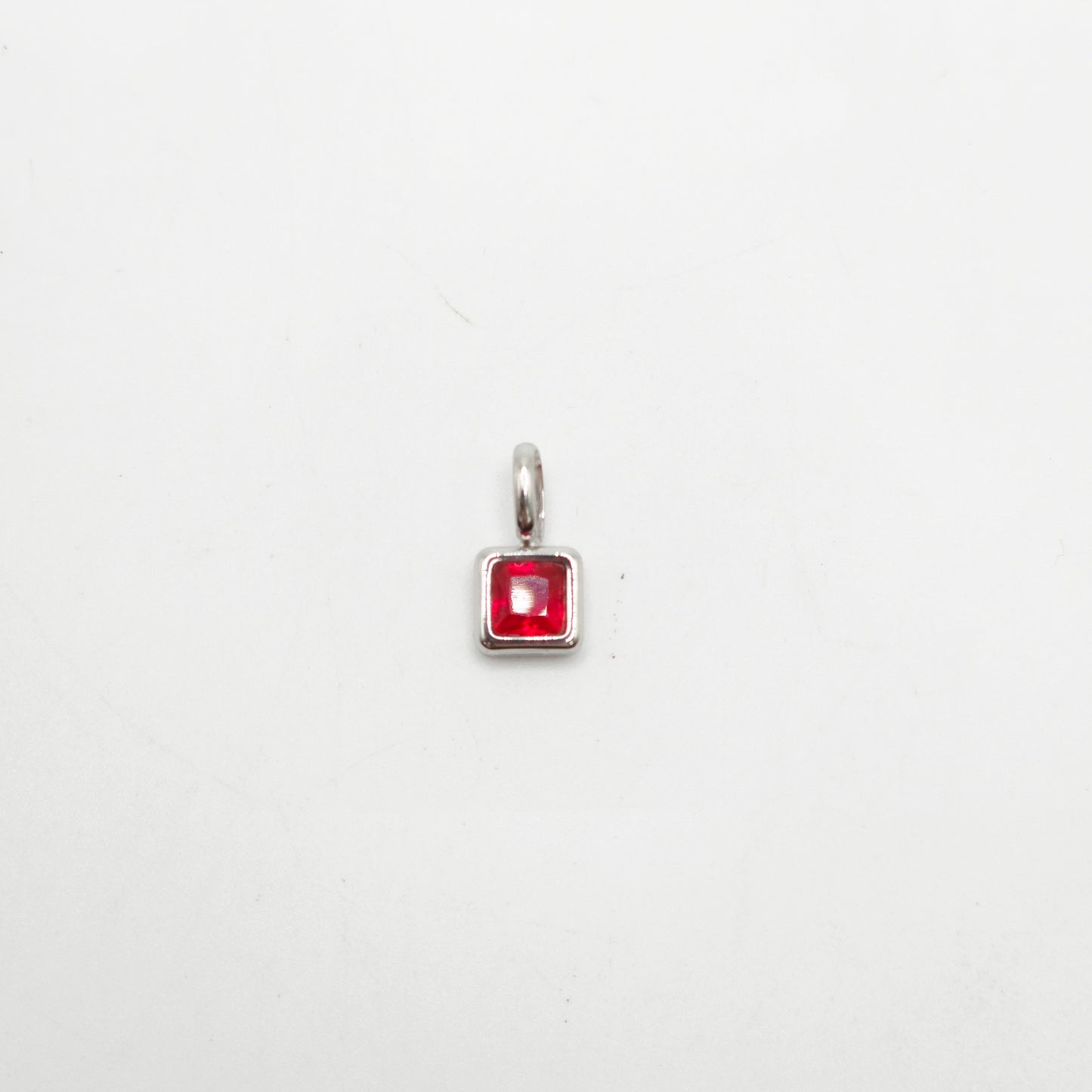 Silver pendant with a red gemstone on a white background