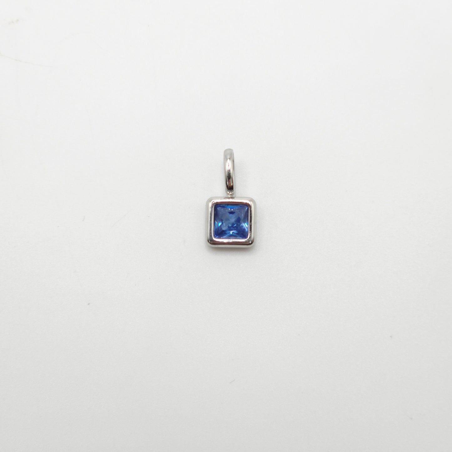 Silver pendant with a blue gemstone on a white background