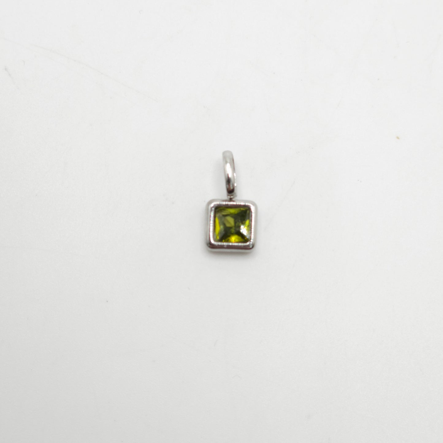 Silver pendant with a green gemstone on a white background