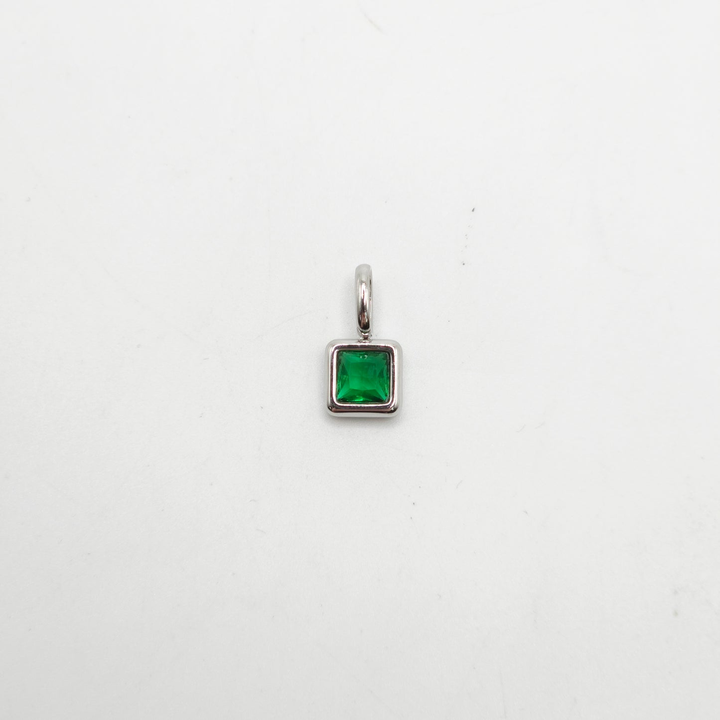 Silver pendant with a green gemstone on a white background
