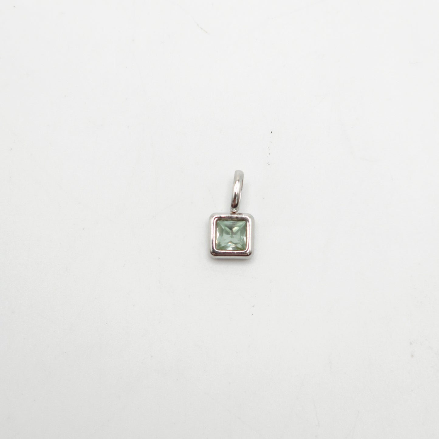 Silver pendant with a green gemstone on a white background