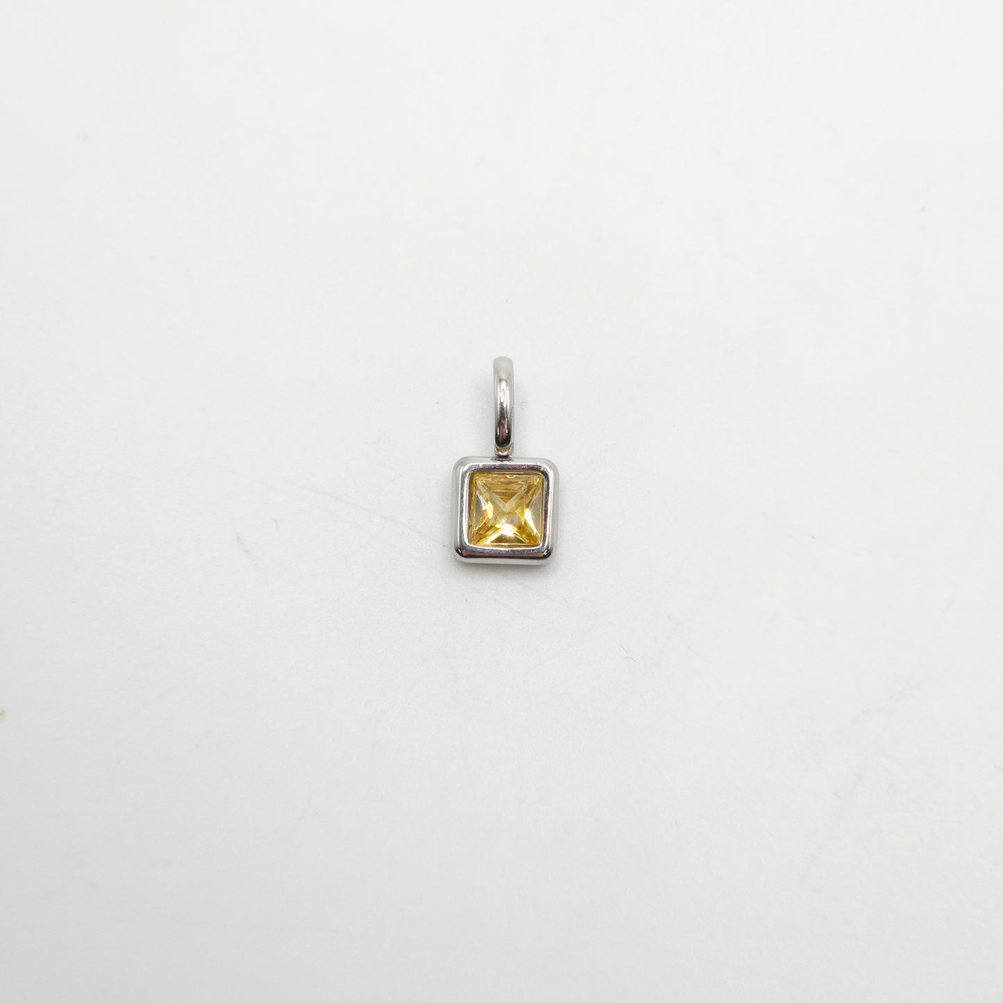 Silver pendant with a yellow gemstone on a white background