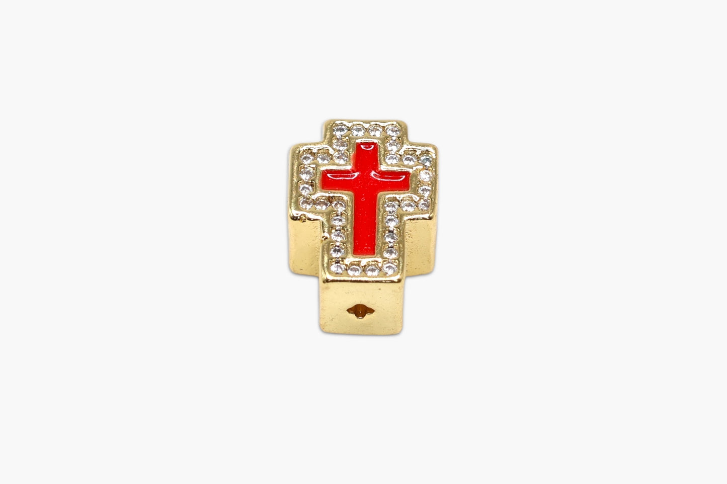 Gold cross charm with a red center on a white background