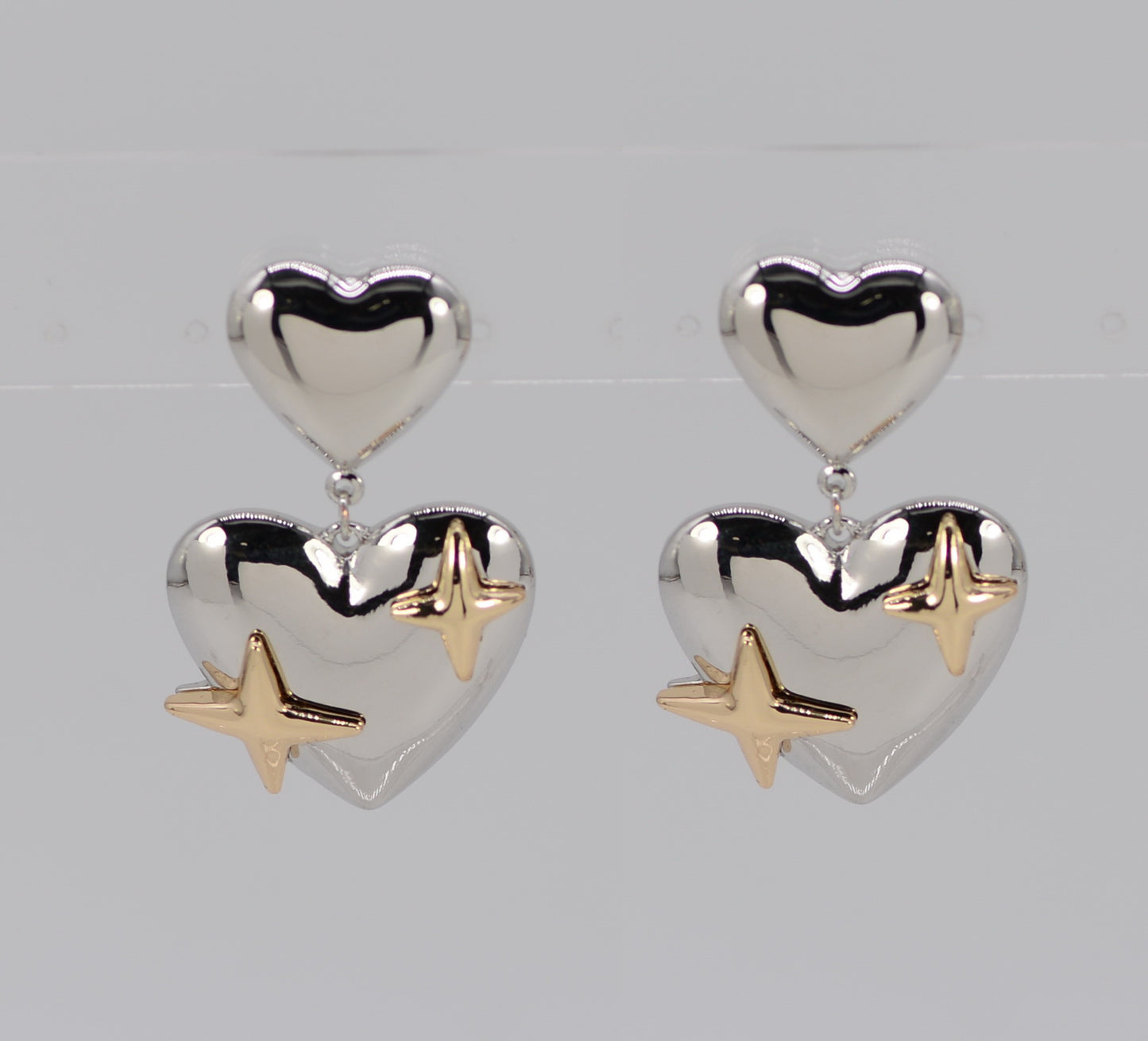 Heart-shaped earrings with gold star accents on a light gray background