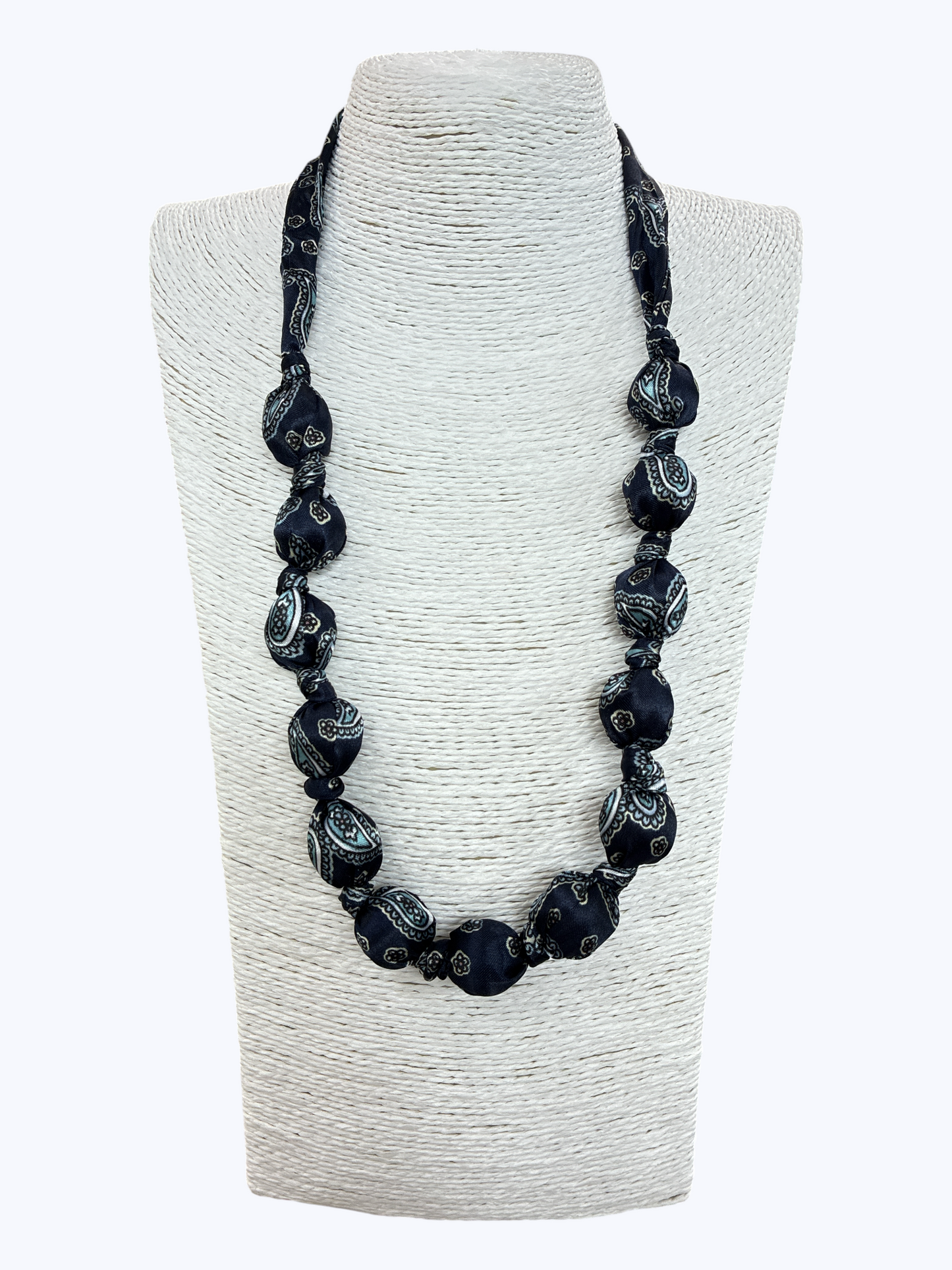 Black beaded necklace on a textured white stand