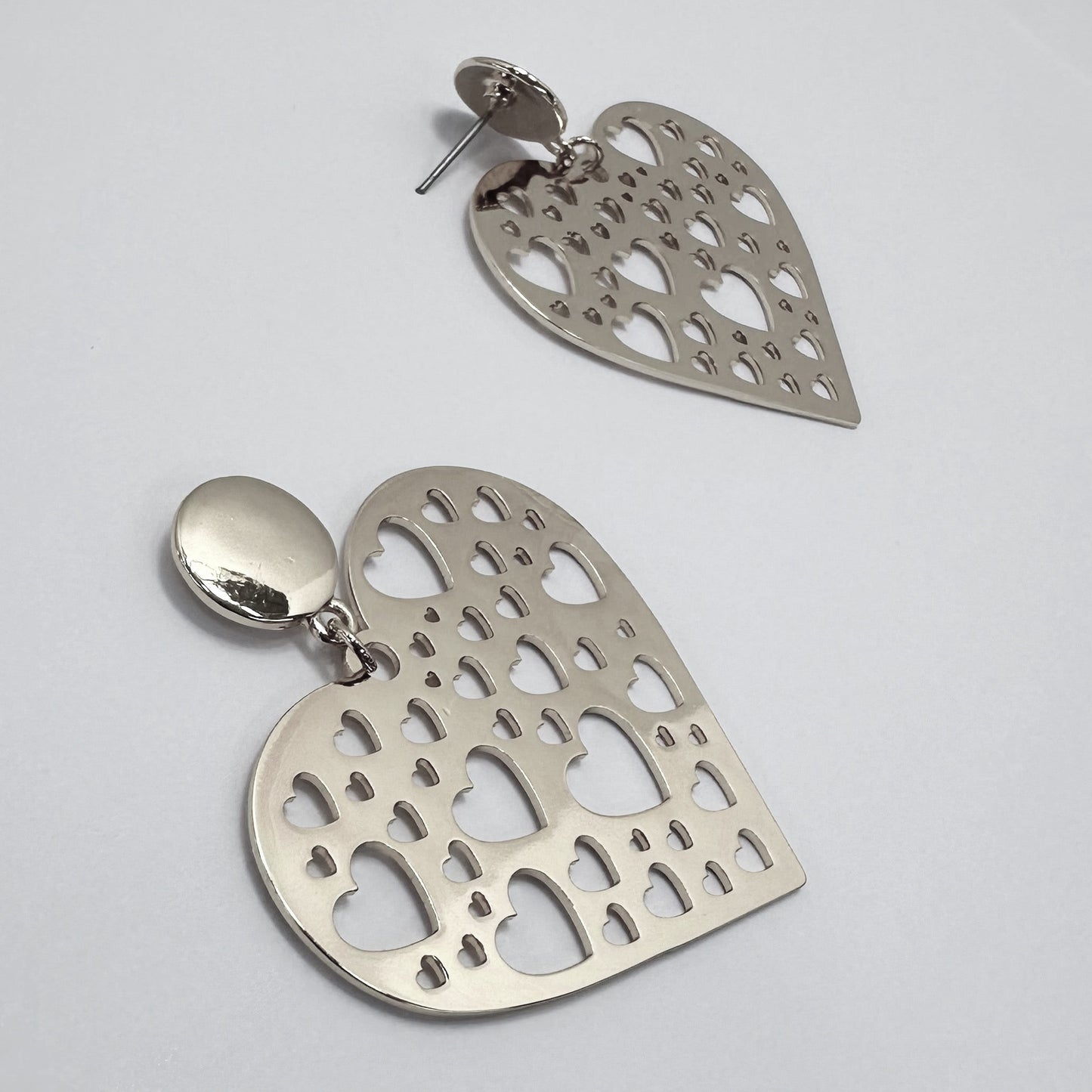 Silver heart-shaped earrings on a light gray background