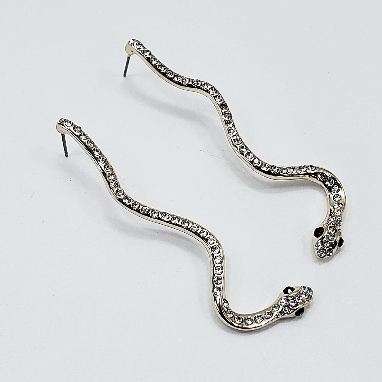 A pair of silver serpent earrings on a white background