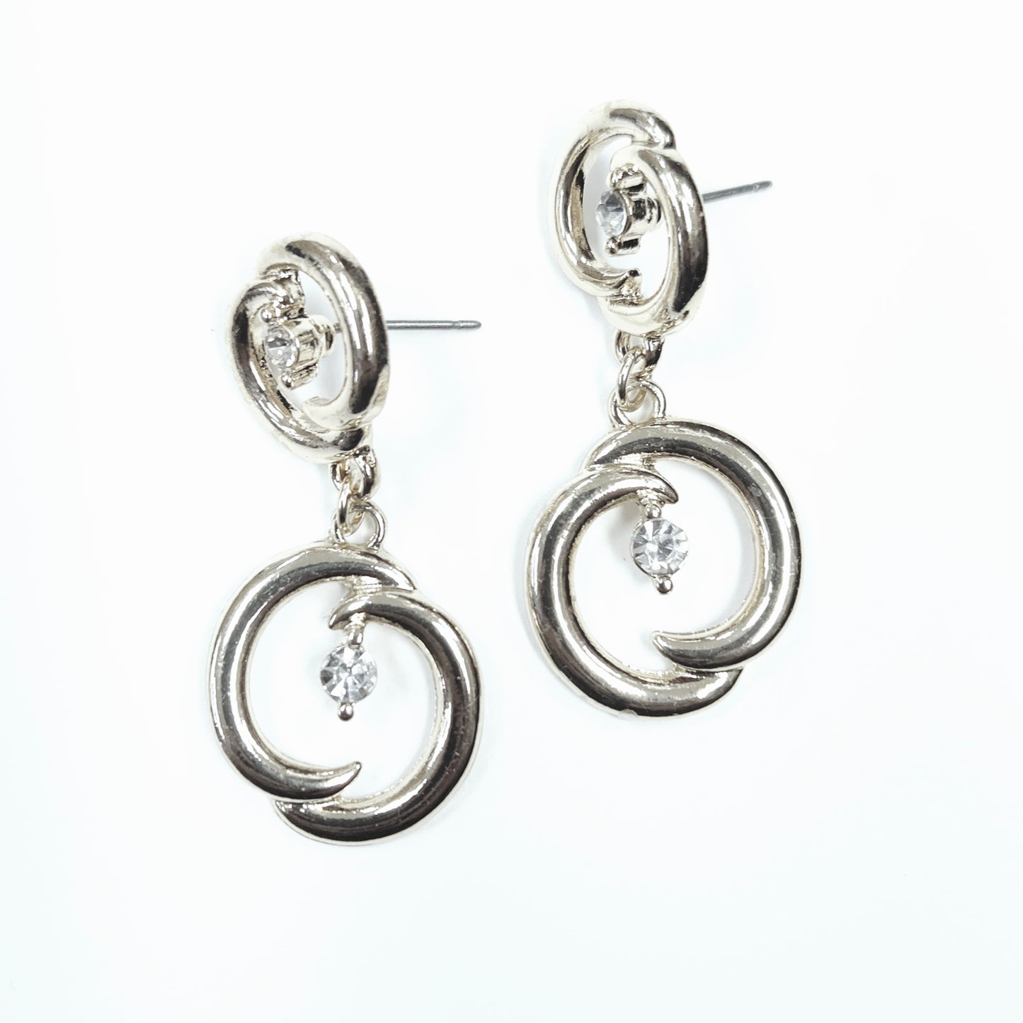 Silver earrings with circular designs and small stones on a white background
