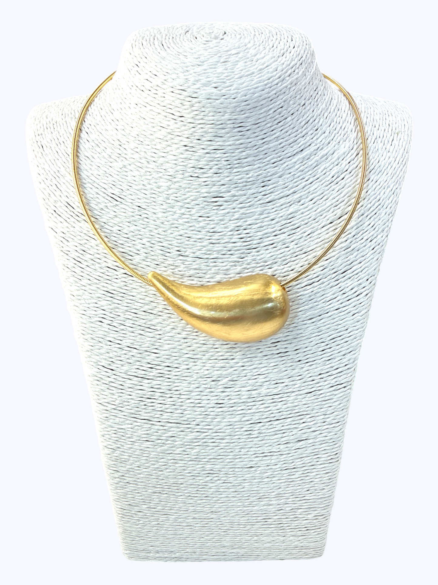 Gold necklace on a textured white stand
