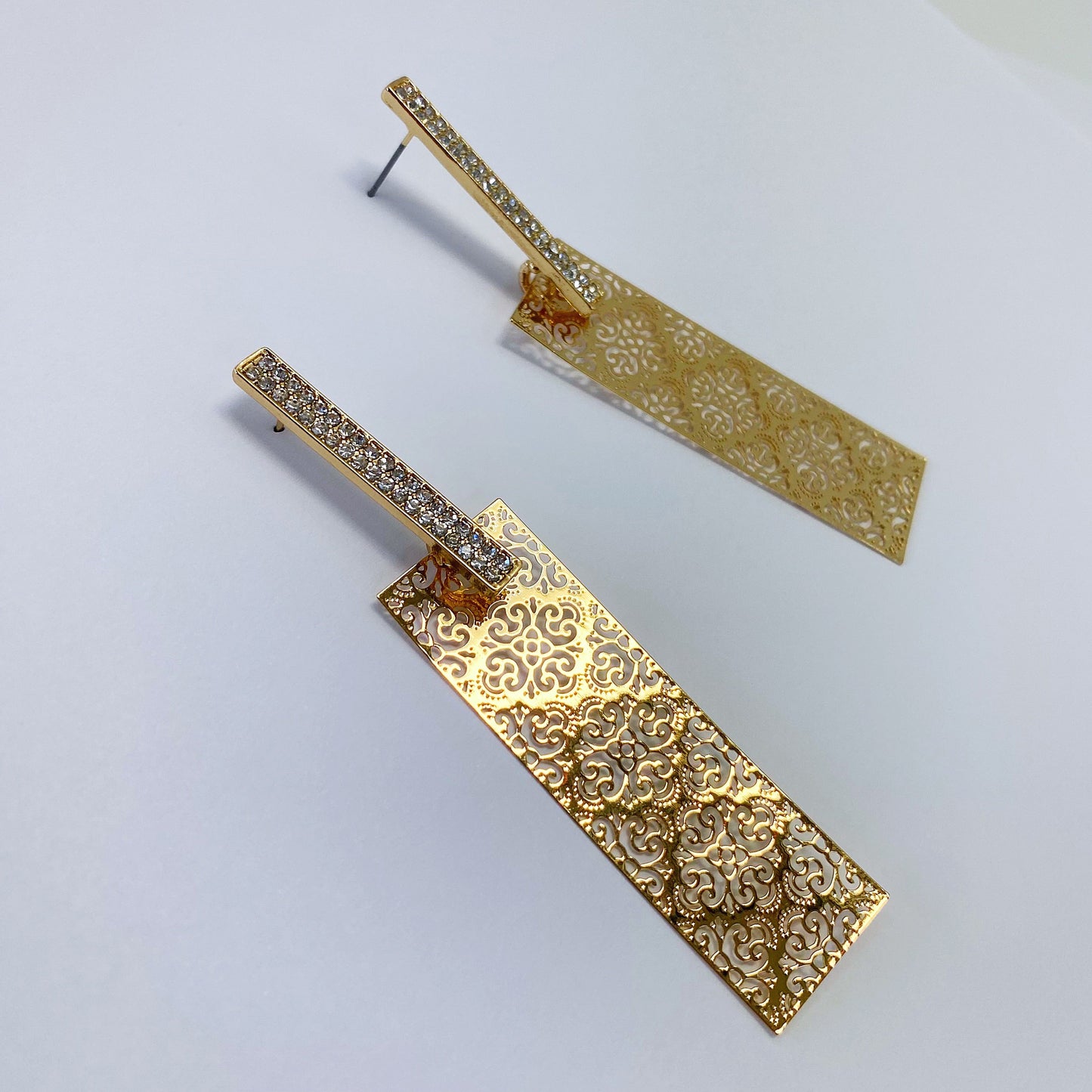 A pair of gold earrings on a white background