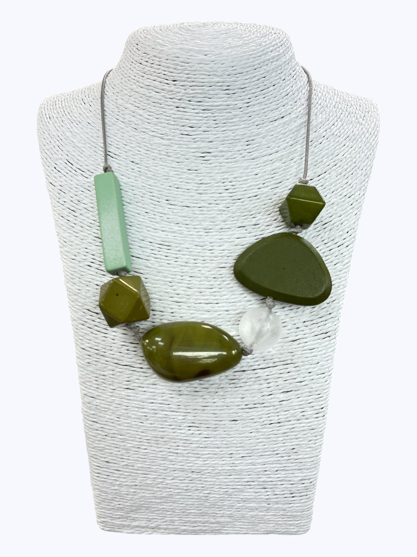 Abstract green geometric statement necklace with mixed oversized beads and modern asymmetrical design on display bust