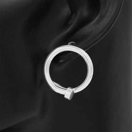 Silver hoop earring on an ear against a dark background
