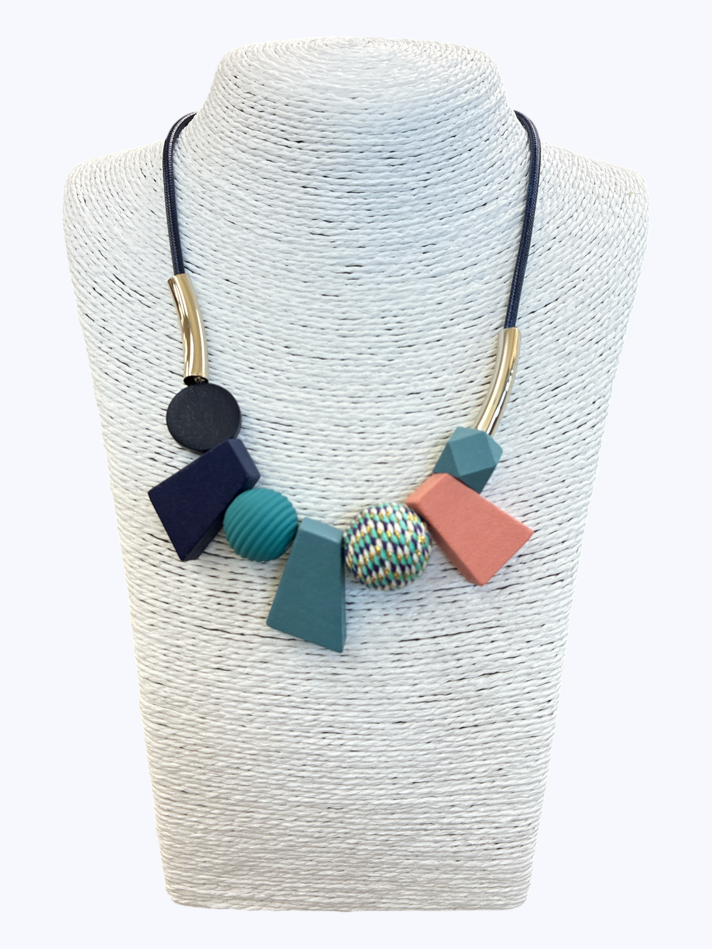 Abstract geometric statement necklace with navy, teal, blush, and textured bead accents on black cord for a bold contemporary boutique style.
