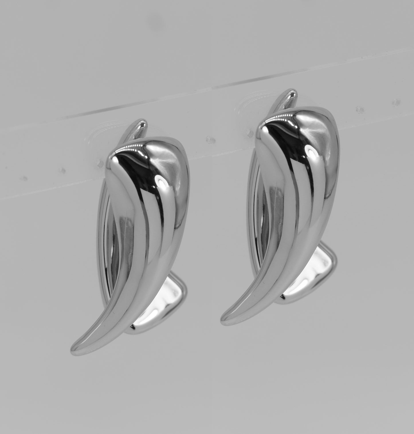 Pair of silver leaf-shaped earrings on a light gray background