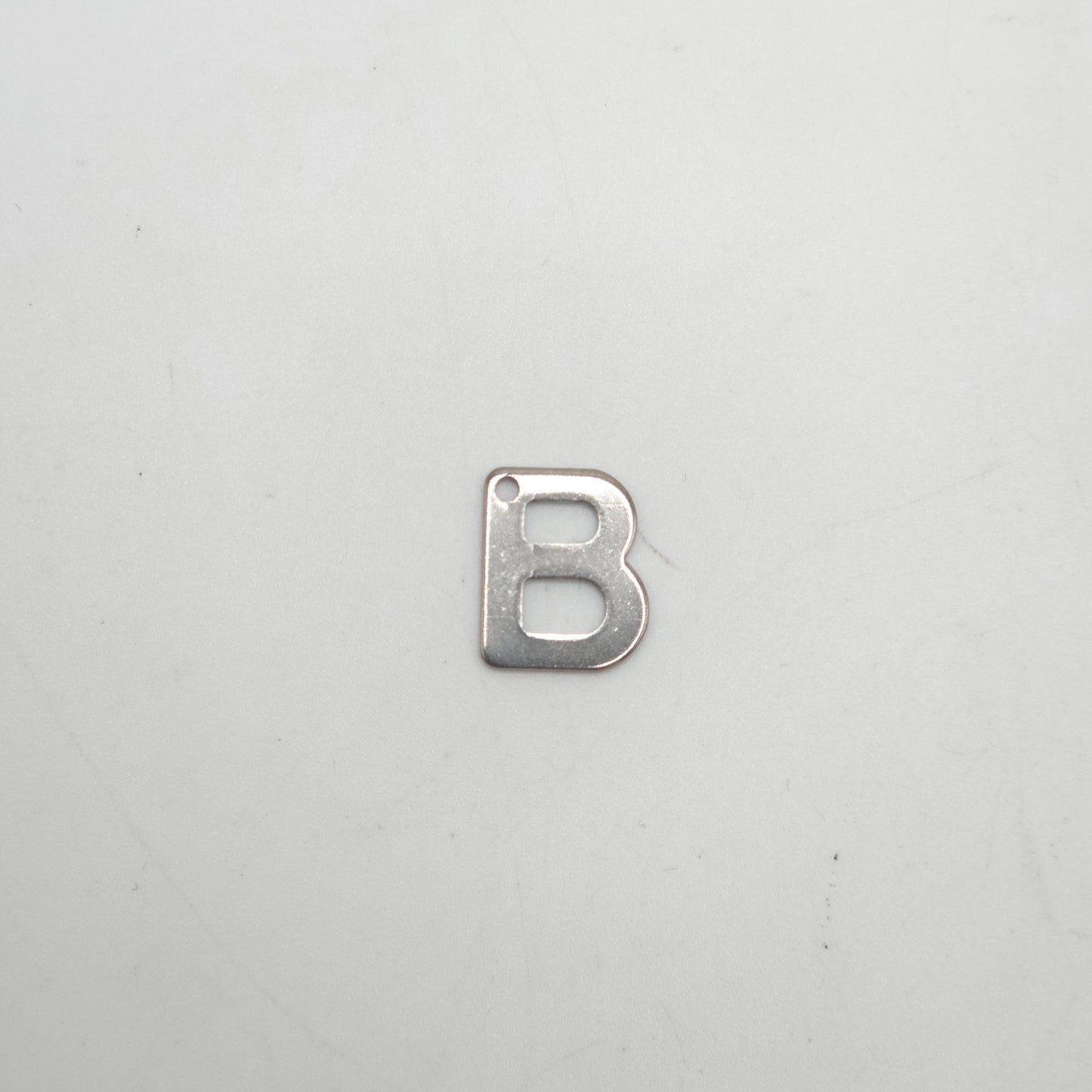 Silver letter 'B' charm on a light gray background