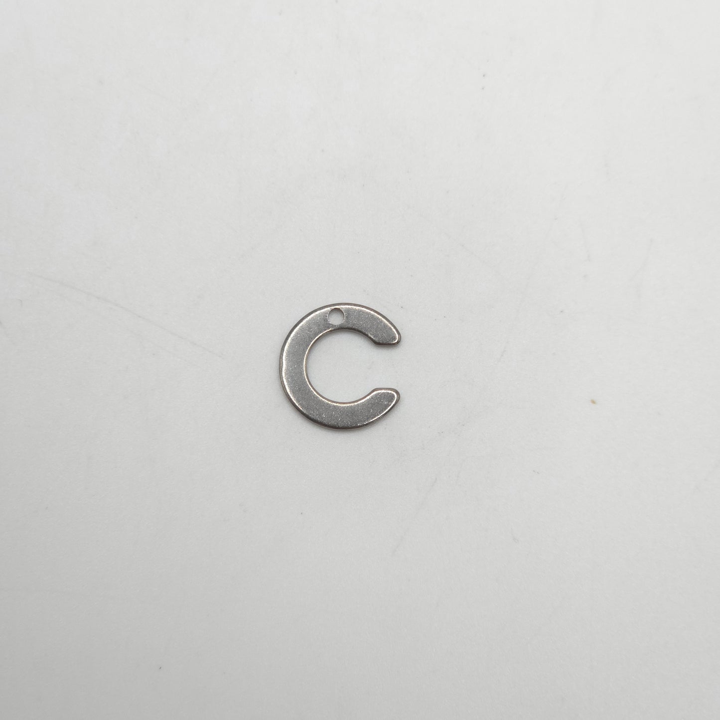 Metallic letter 'C' charm on a white background