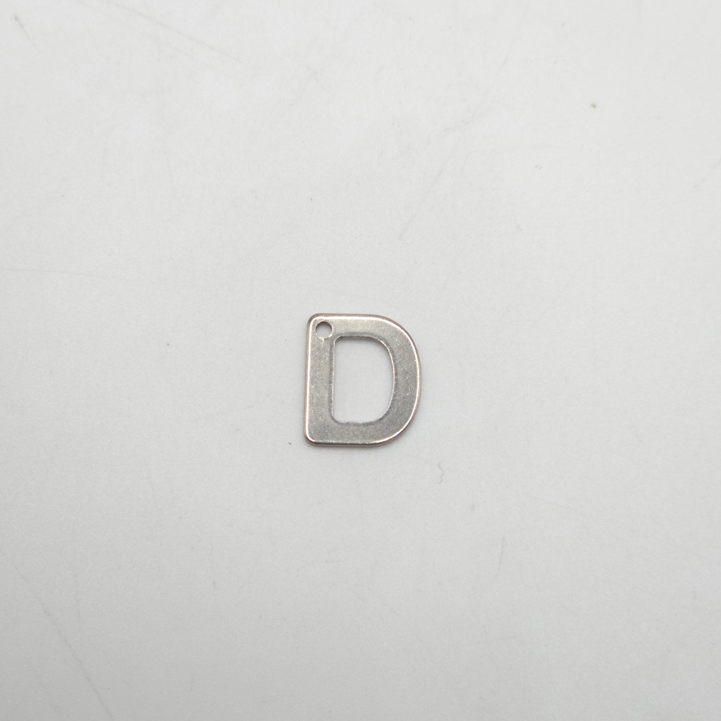 Silver letter 'D' charm on a light gray background
