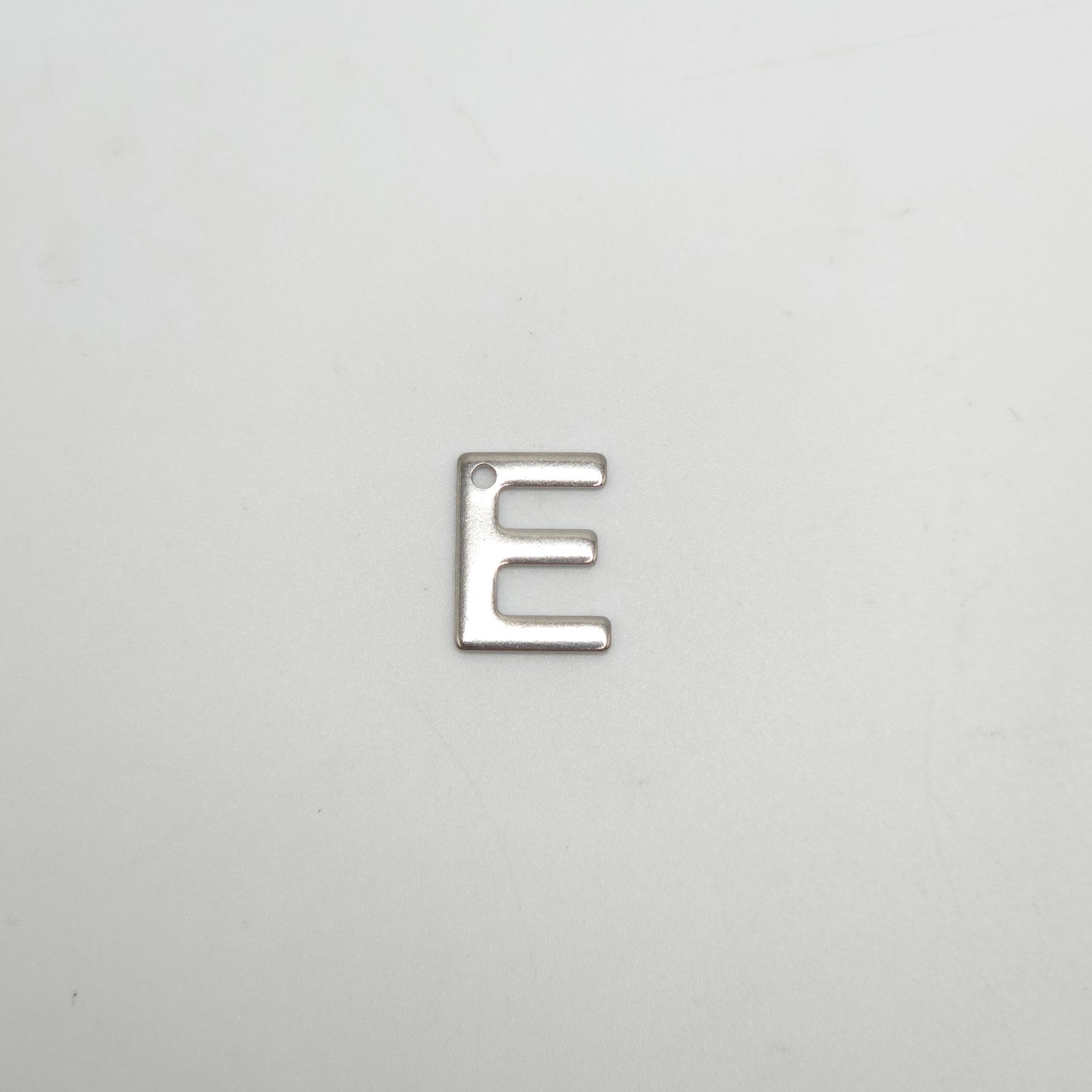 Silver letter 'E' charm on a light gray background