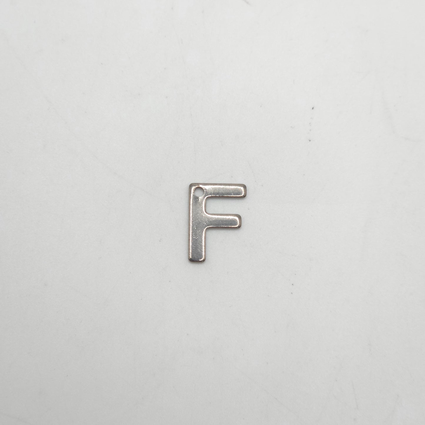 Silver letter 'F' charm on a white background