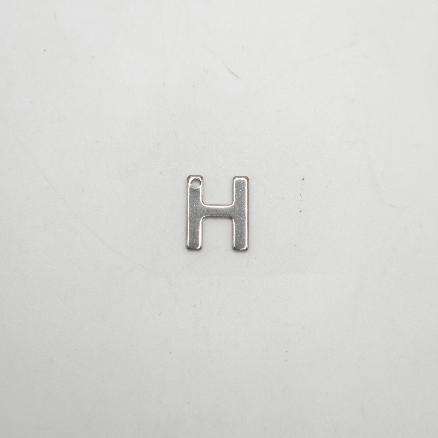 Silver letter 'H' charm on a white background