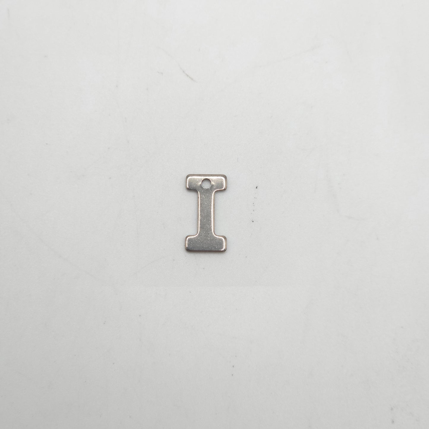 Metallic letter 'I' charm on a white background