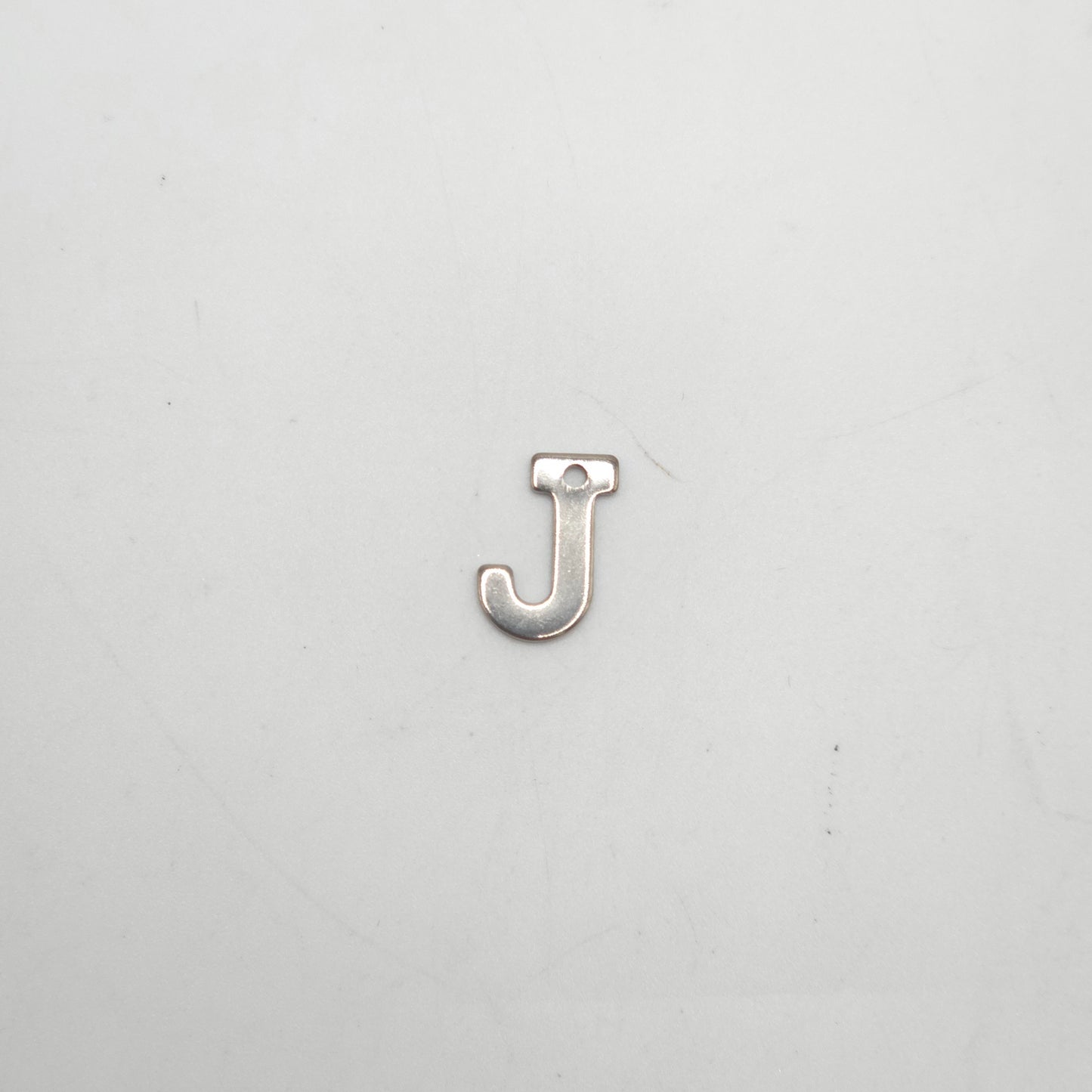 Silver letter 'J' charm on a light gray background