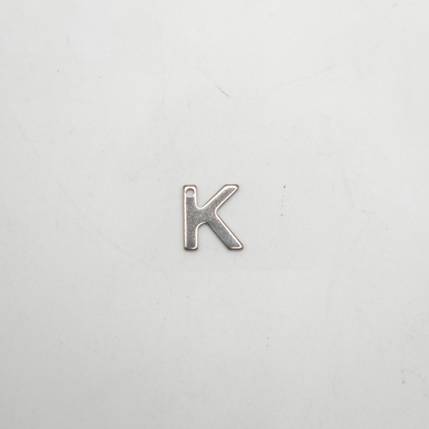 Silver letter 'K' charm on a white background