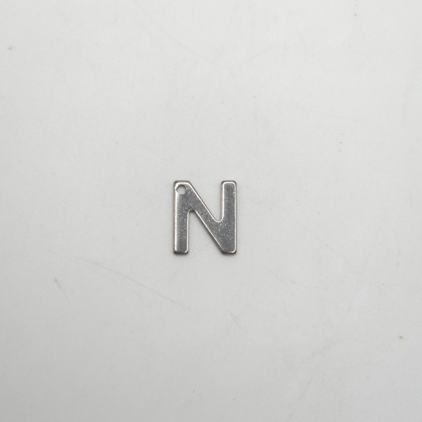 Silver letter 'N' charm on a light gray background