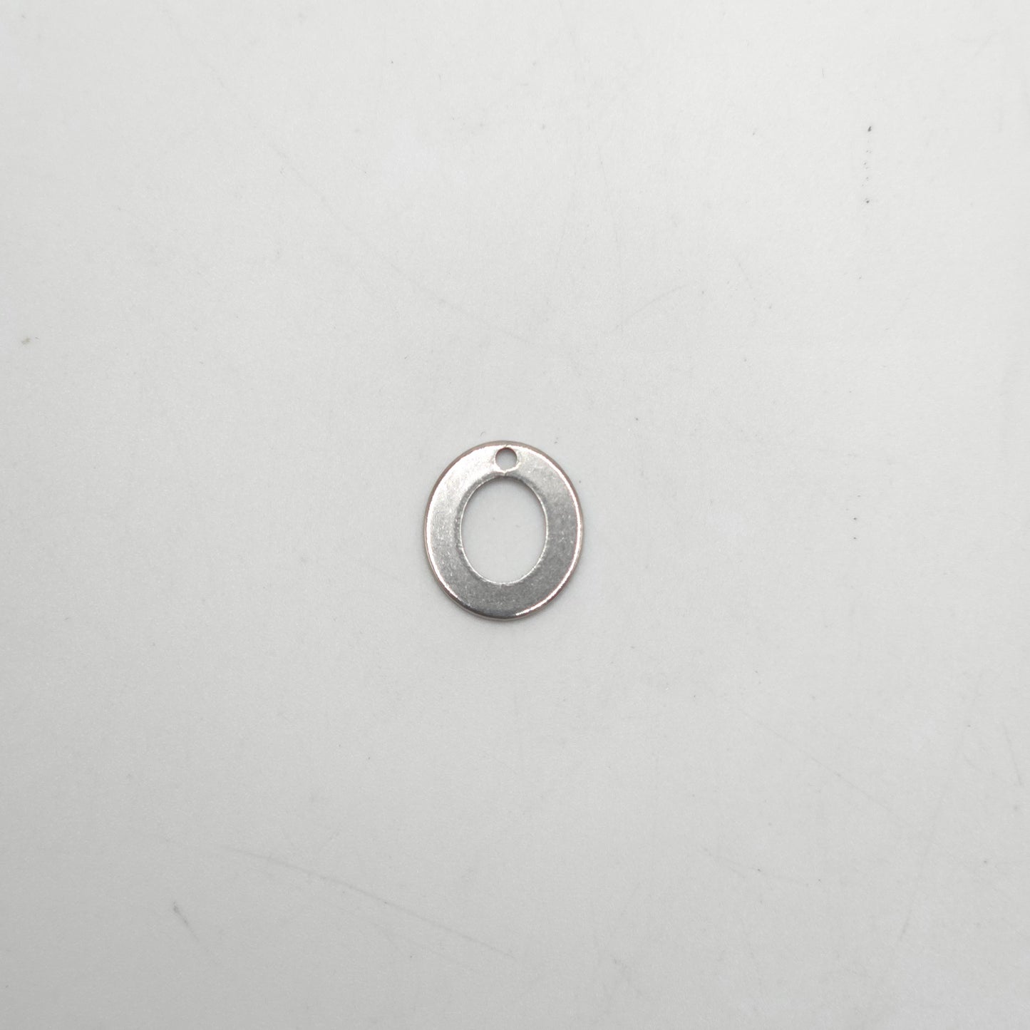 Silver pendant shaped like the letter 'O' on a light gray background