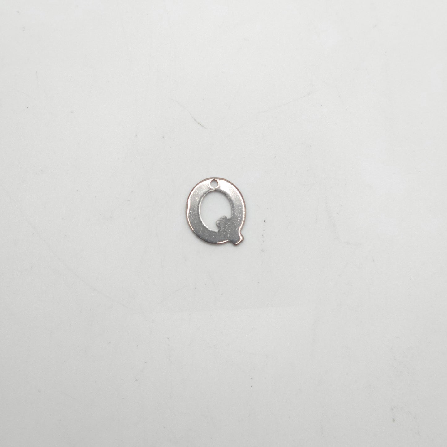 Silver letter 'Q' charm on a white background