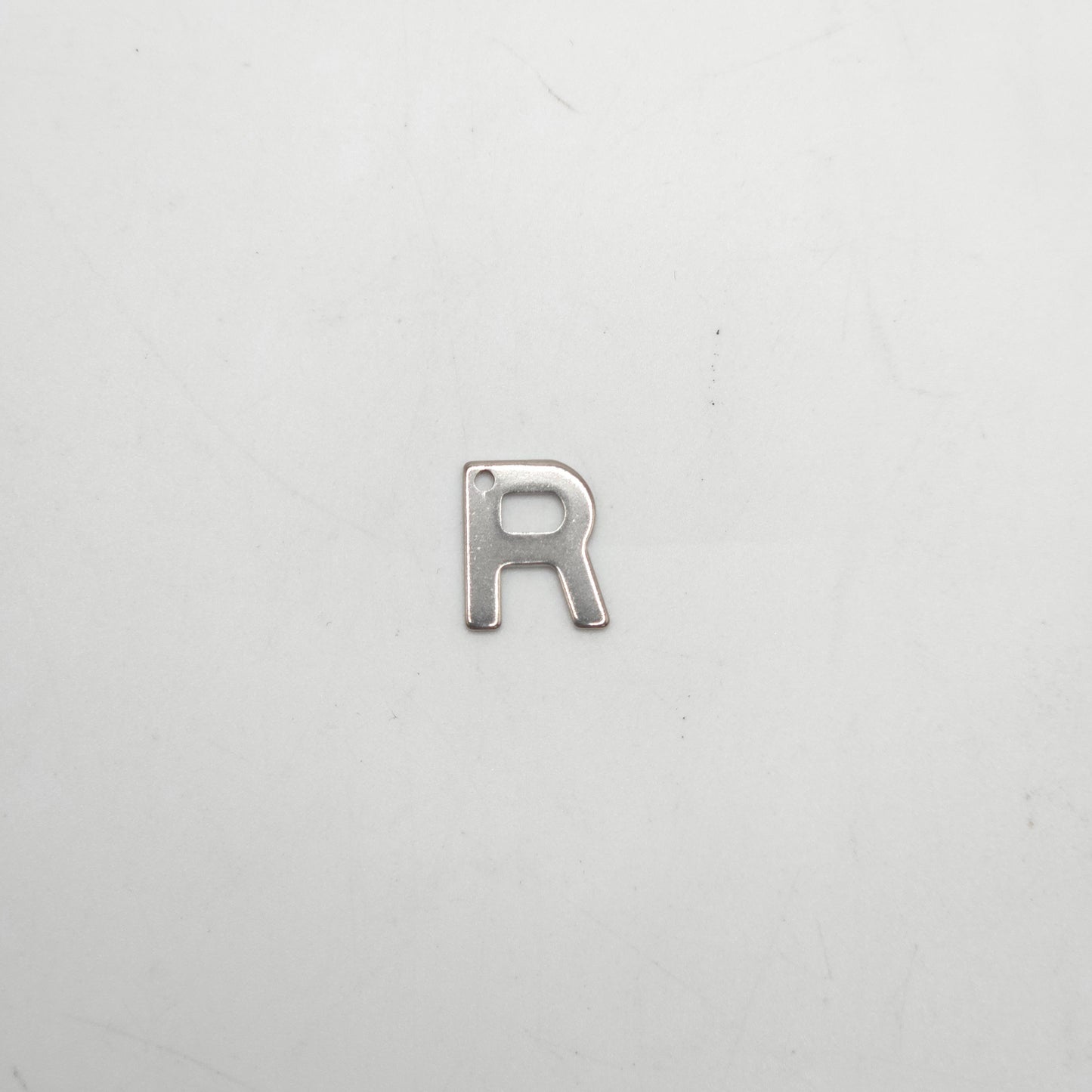 Silver letter 'R' charm on a white background