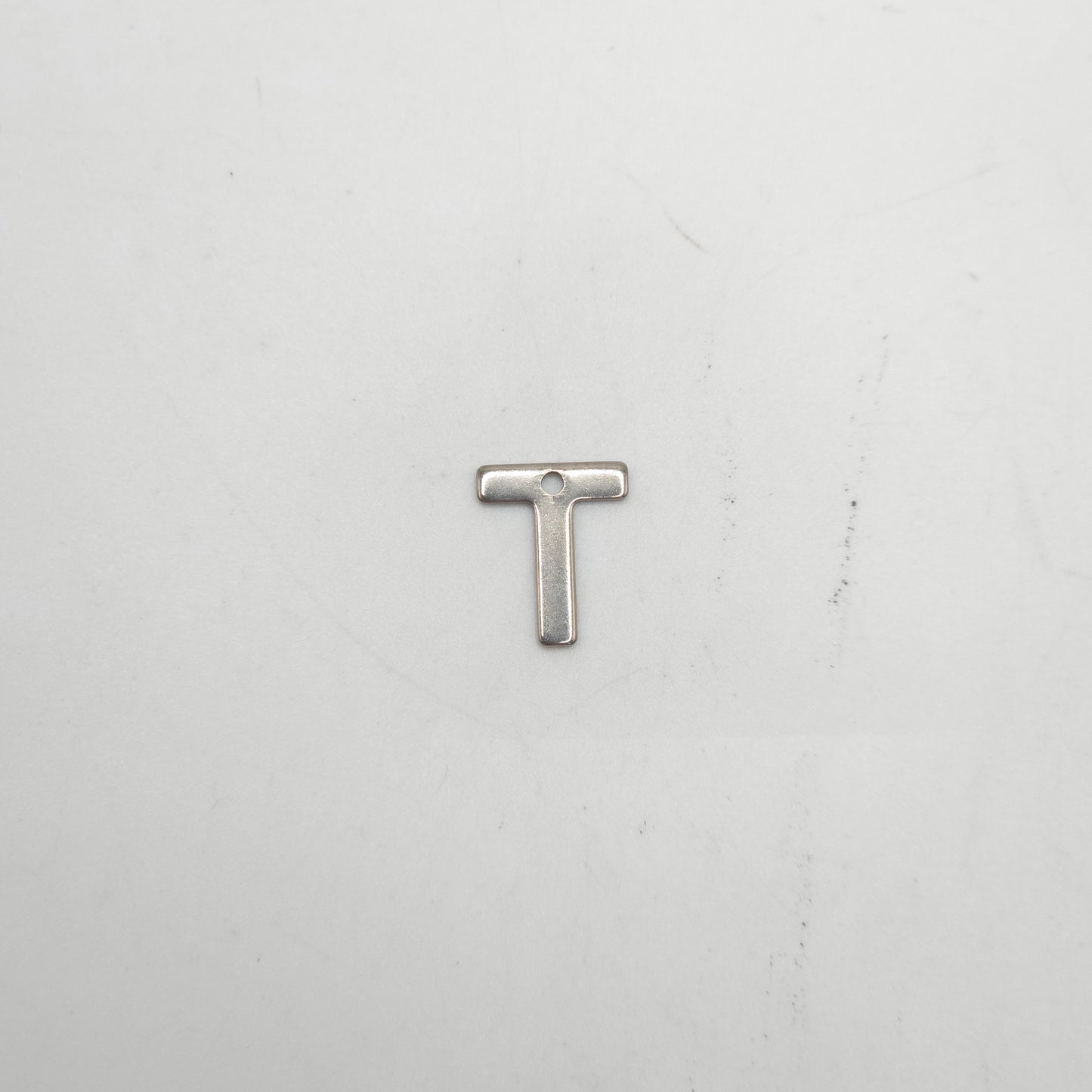 Silver letter 'T' charm on a white background