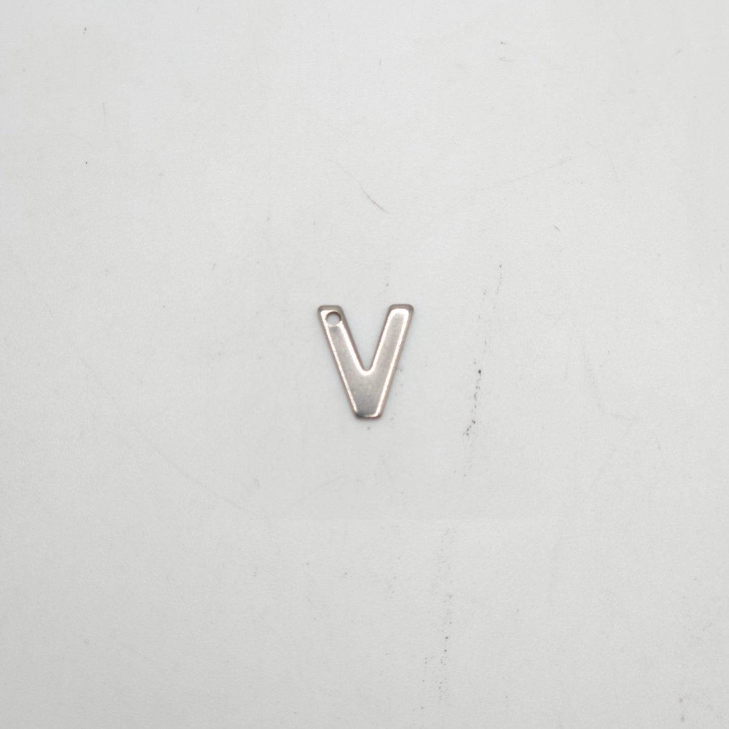 Silver letter 'V' charm on a light gray background