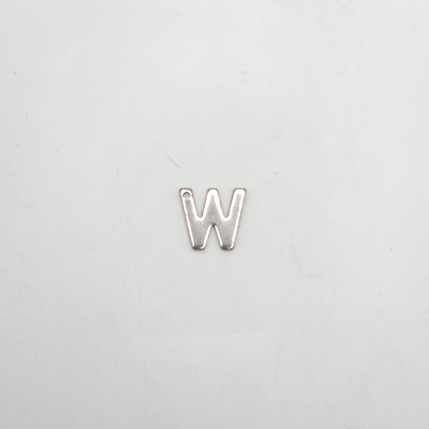 Silver letter 'W' charm on a light gray background